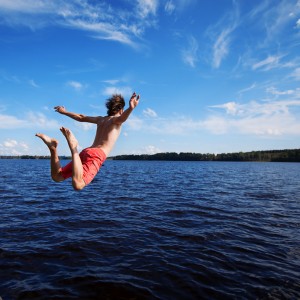Young man jumping into water, summer time